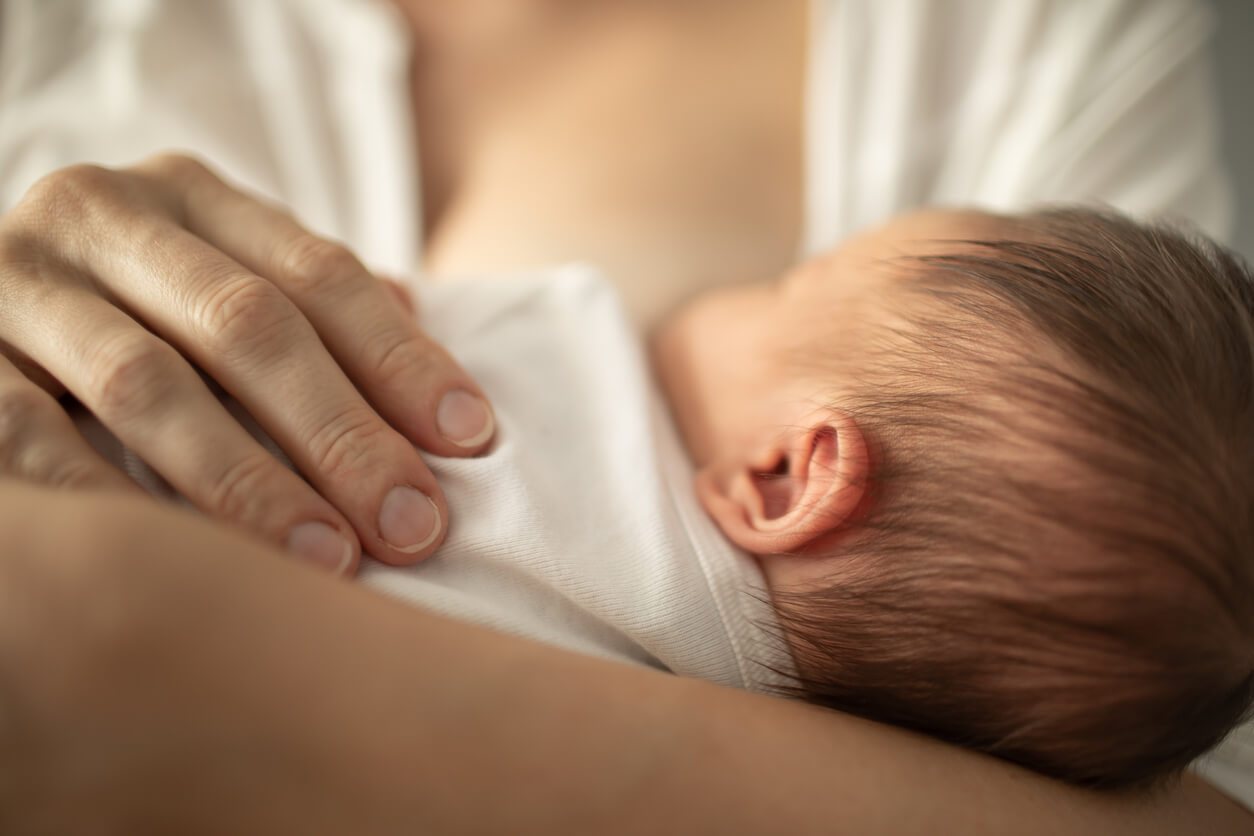 Newborn baby girl breast feeding in mothers arms