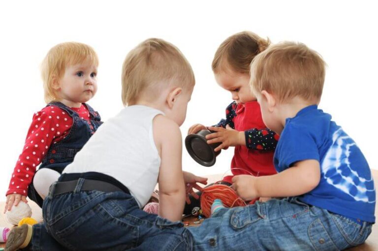 Four toddlers are playing with yarn and buttons