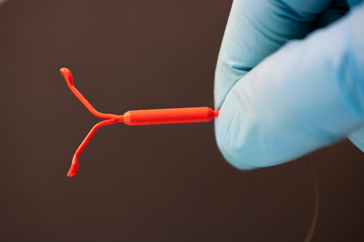 Gloved hands holding control with copper IUD