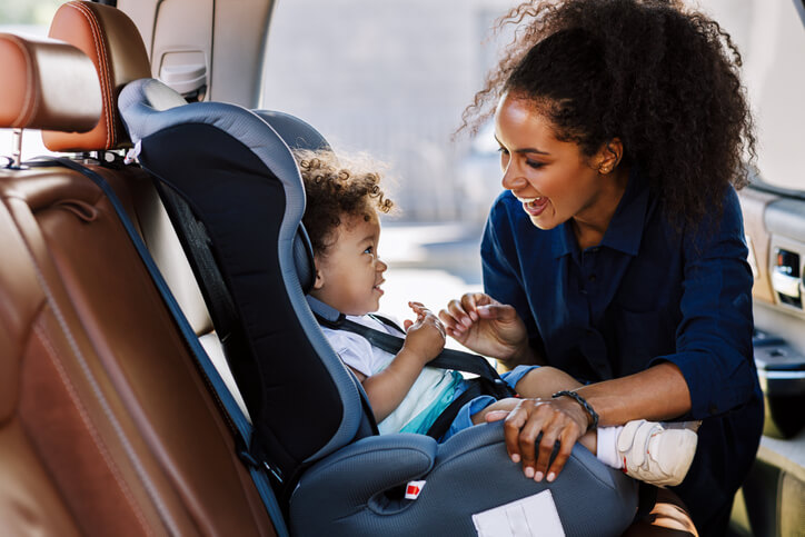 Happy mother looking at her son in a baby seat