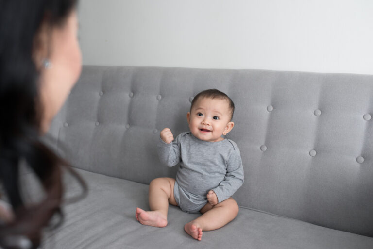 Young mother with her one years old little son dressed in pajamas are relaxing and playing in the living room