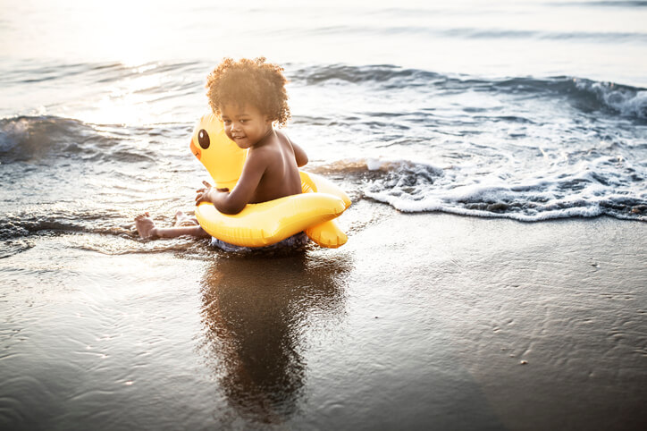 Cute toddler with duck tube on the beach