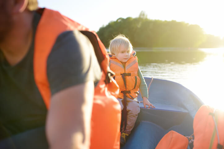 Mature father and little son boating on a river or pond at sunny summer day