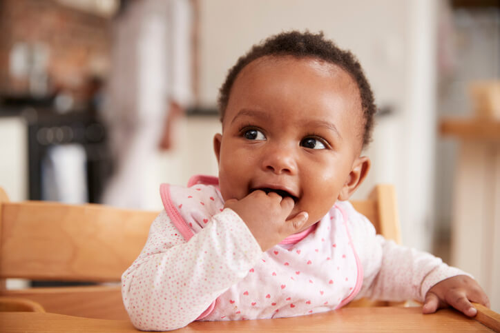 Cute Baby Girl Wearing Bib Sitting In High Chair