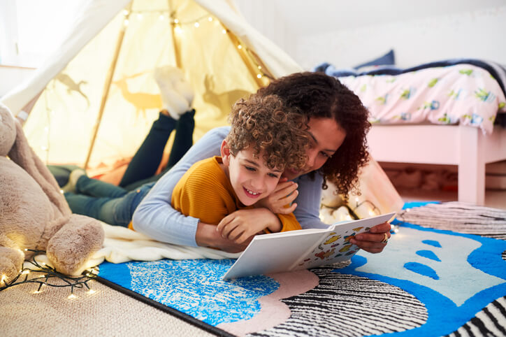 Single Mother Reading With Son In Den In Bedroom