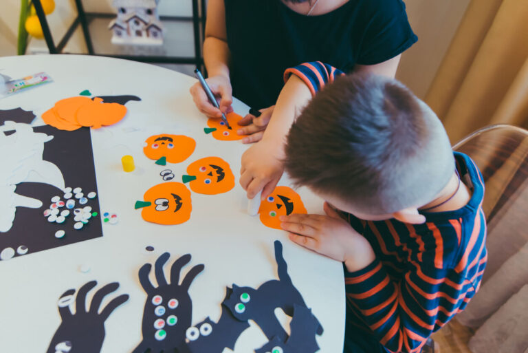 Young mother with toddler son making craft pumpkins for halloween