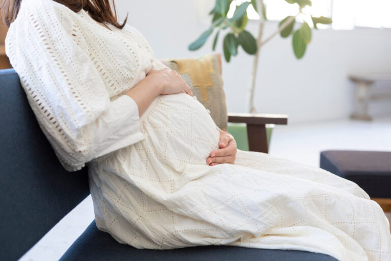 Pregnant woman sucking belly in the room