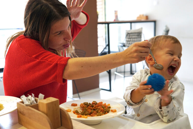 nhappy child refusing to eat at a restaurant with white background