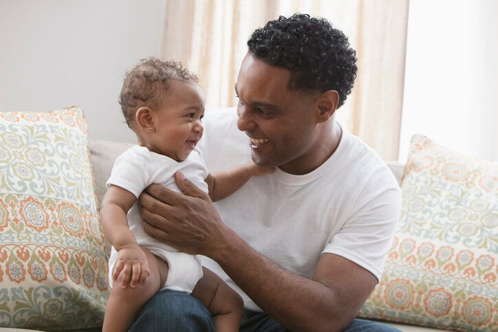 ather playing with his daughter sitting at the sofa