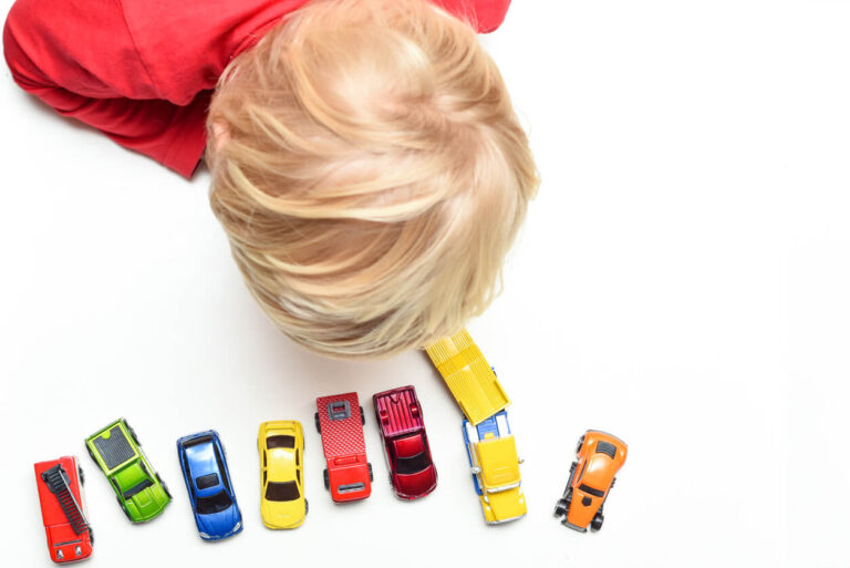 Boy plays with toy cars at home high angle