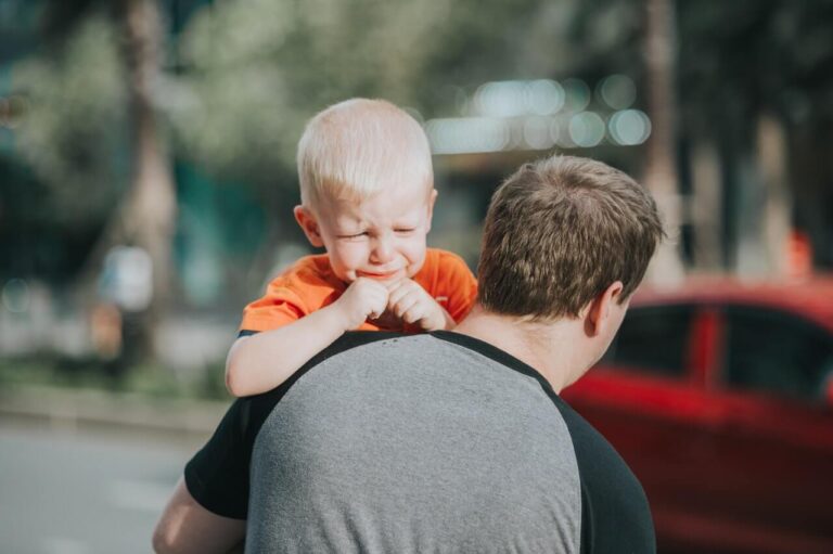 a dad carrying his son who is having a tantrum