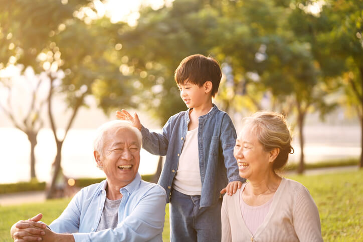 two grandparents playing with their grandchild outside