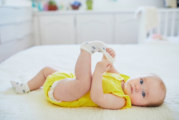 dorable baby girl removing sock from her foot