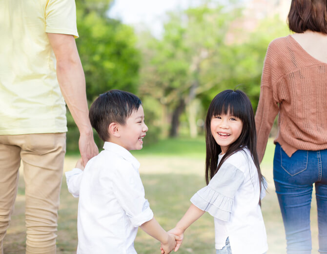 two young kids holding hands with their parents