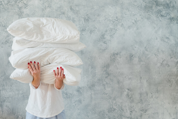 a woman holding a lot of pillows