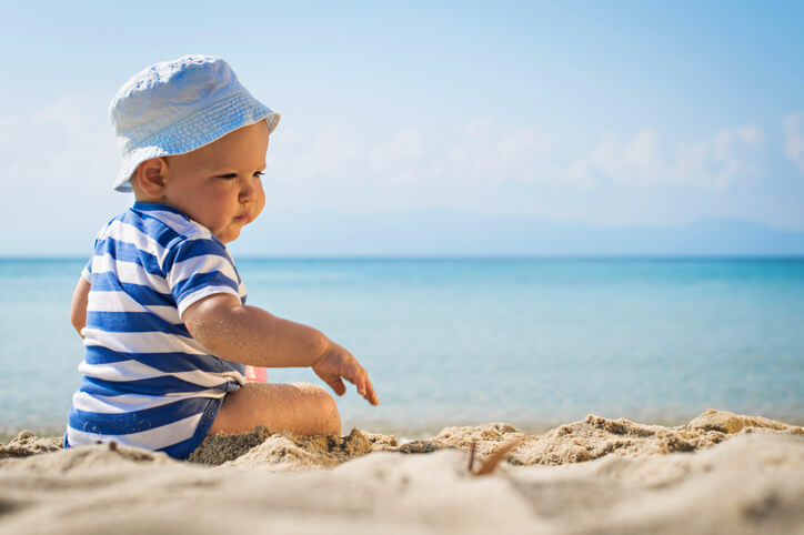 Little baby boy sitting on the sand