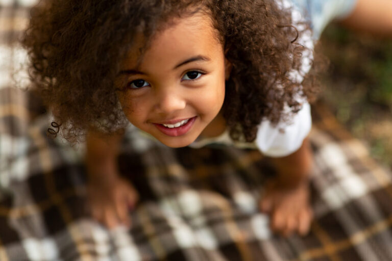 Cute little girl playing on blanket and looking up