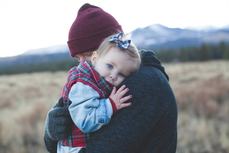 a dad carrying his baby outside in November