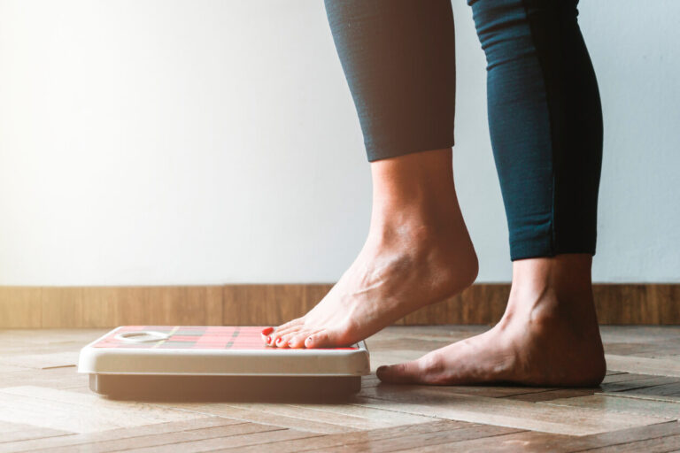 pregnant female checking kilogrammes getting on the scale