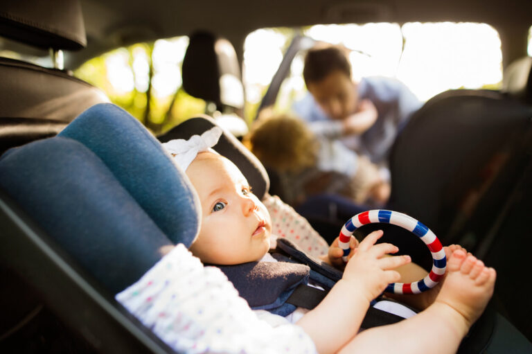 Little baby girl fastened with security belt in safety car seat