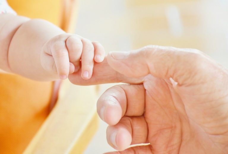 a newborn baby holding his mothers hand