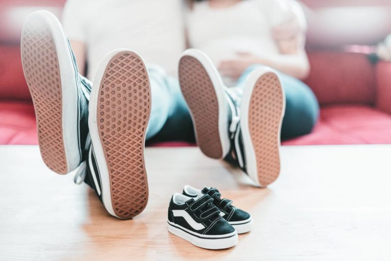 two parents sitting on the sofa showing their shoes