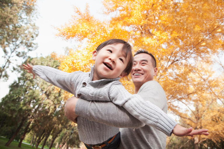 Father and son playing together at the park in autumn