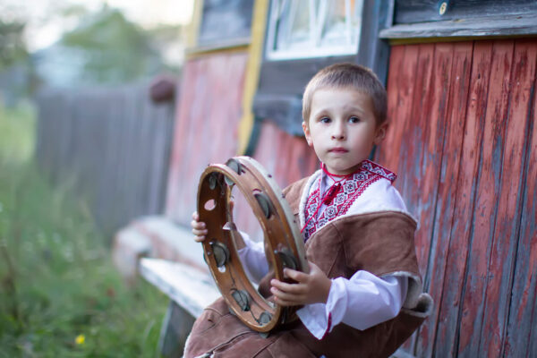 Little boy in Slavic national dress with an ethnic tambourine