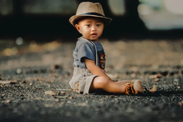 Child In Grey Shorts Sitting On Road